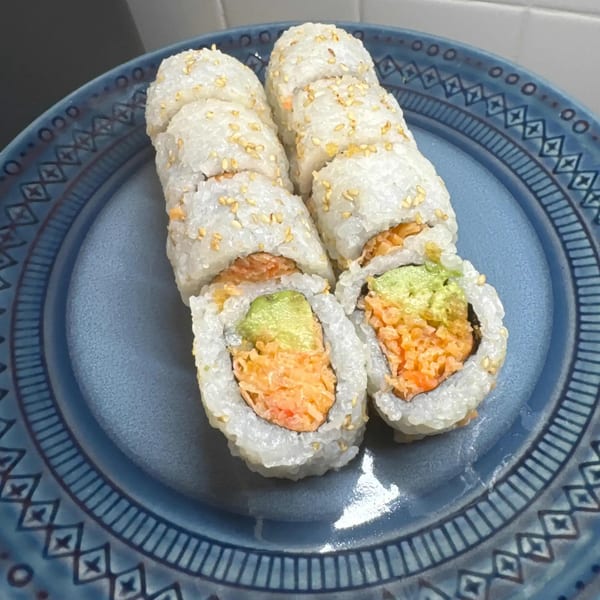 Two rows of Kei Sushi Restaurant's sushi rolls with avocado and salmon on a blue plate.