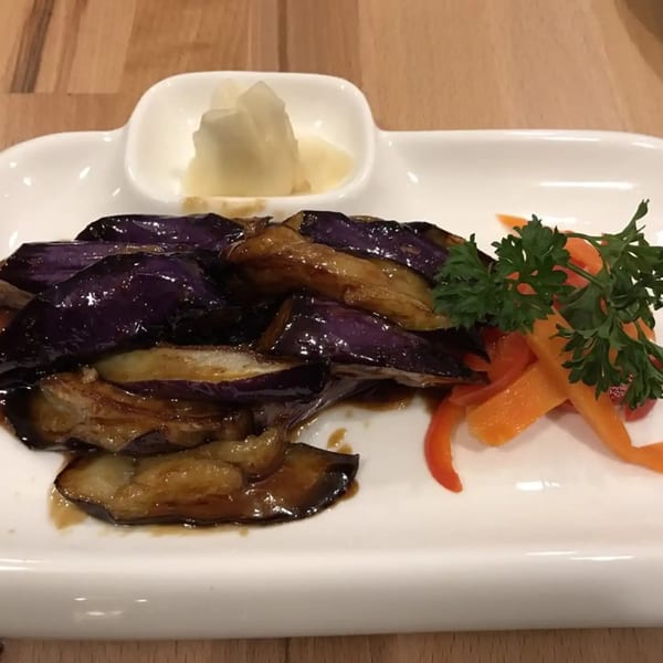 Kei Sushi Restaurant's glazed eggplant dish with pickled ginger, bell peppers, and parsley on a white plate.