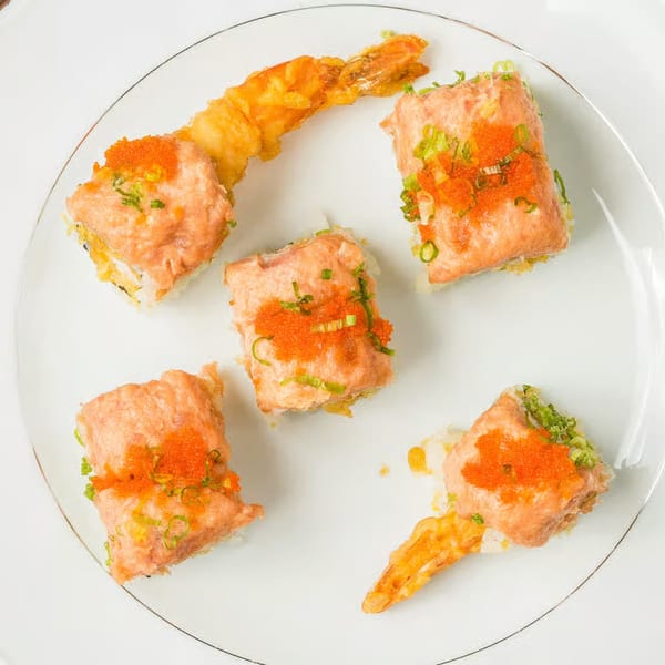 Five Kei Sushi rolls with tempura shrimp, salmon, roe, and green onions on a white plate.