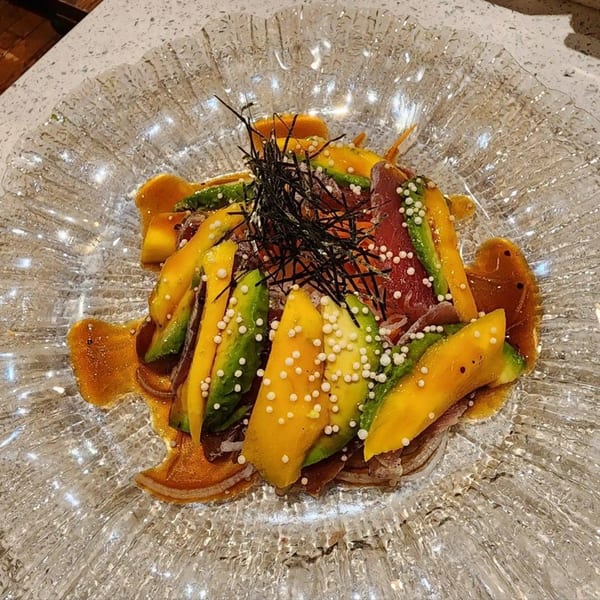 Kei Sushi's tuna sashimi with avocado, mango, seaweed, and white pearls in a clear glass bowl.