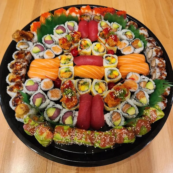A large platter of Kei Sushi Restaurant's diverse sushi rolls and sashimi on a wooden table.